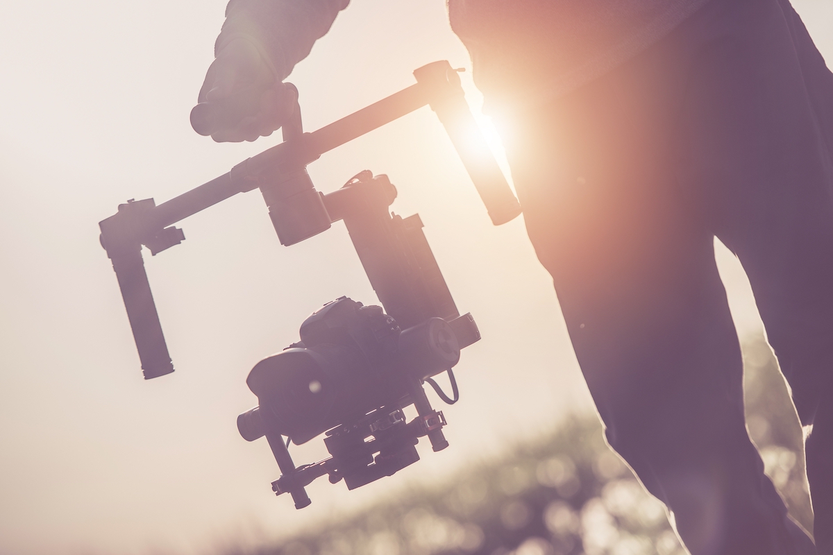 Videographer operating a camera gimbal at golden hour